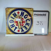 Metal Hockey Night In Canada sign positioned upright with measurement scale showing approximately 12 inches in width.