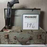 Omark 330 powder actuated tool upright in open metal carrying case with visible wear on case and tool handle