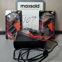 Wide shot showing three unopened triple vehicle outlets in original packaging and one UV money scanner with carrying case and power cord.