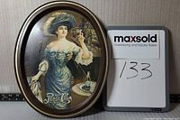 Oval metal Pepsi Cola tray with vintage artwork of a woman holding a glass, with Pepsi bottle and glasses on table. Shows signs of age and wear.