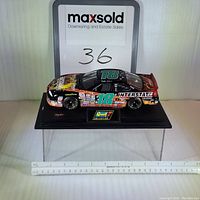 Front side angle of the black Pontiac Grand Prix die-cast model car with racing decals and number 18, on a Revell Collection labeled display base with a ruler for scale.