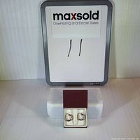 Sterling silver hoop earrings displayed on a white background with a MaxSold sign behind them.