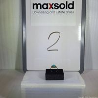 Photo of turquoise sterling silver ring displayed on black foam with MaxSold sign in background
