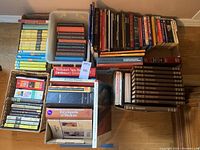 Overview of multiple stacks of hardcover books arranged on floor including children's series, Time Life books, dictionaries, and encyclopedias.