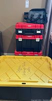 Three stacked red and black Craftsman Verstack tool boxes and a large black and yellow storage bin with lid, with a canvas tool bag on top.
