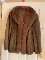 Full frontal view of brown fur coat showing thick fur and large collar, hanging on a door.