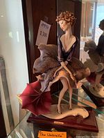 Full front view of the porcelain sculpture displayed on glass shelf