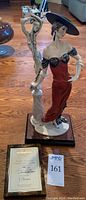 Full front view of porcelain sculpture on wood base with certificate and auction tag visible