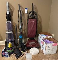 Overall view of 3 cleaning machines, bottles of cleaning solution, microfiber cloths in boxes, and some accessories arranged on floor.