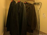 Photo of 3 jackets hanging on hangers in closet, showing black leather and dark brown suede materials