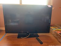 Full view of LG 42 inch LCD TV on stand with remote in front.