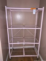 Full view of the four-tier wire mesh shelving rack with blush pink metal frame, showing overall structure and shelving.