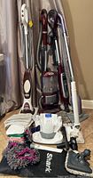 Full lot shot showing vacuum, floor mop, steamer, accessories and mop heads grouped on floor