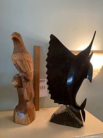 Both wood carvings together showing the raptor on the left and the marlin on the right with ruler for size reference