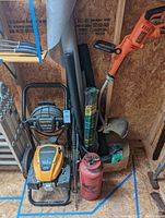 Photo showing Black & Decker weed wacker with trimmer line, WorkForce pressure washer engine and hoses, Ace red metal sprayer, and rolls of landscaping fabric including WeedBlock film.