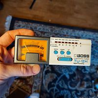 Front view of the Boss TU-12H tuner showing yellow analog meter, pitch control and tuning switch.