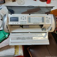 Front view of Cricut George and Basic Shapes cutting machine with keyboard, screen, and open cover