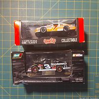 Two Quartzo and Revell Collectibles NASCAR model cars in their original packaging; one Quartzo car is loose inside the box.