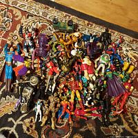 Photo of a large mixed lot of action figures including Marvel, DC, Spawn, wrestling, Star Wars, TMNT and Power Rangers, showing various characters and some toy vehicles on a patterned carpet.