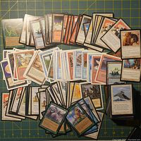 Photo showing multiple Magic The Gathering cards spread out, front side visible with various card types and artwork.
