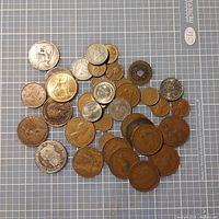 Photo showing a diverse lot of 34 old coins of various sizes, metals, and origins on a measurement grid background.