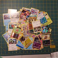 A pile of assorted Pokemon trading cards showing many different Pokemon characters, some holo cards visible.