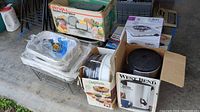 Photo showing Rival food slicer box atop metal pans with wire frames and other boxed appliances around