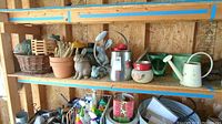 Wide view of shelves showing various garden items including animal statues, watering cans, metal buckets, and baskets