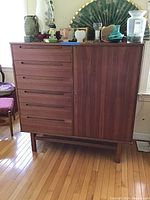 Front left-angled view showing six drawers and right cabinet door on raised leg frame