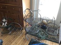 Photo showing a variety of metal baskets of different sizes and styles, along with decorative balls and a dream catcher on the floor in front of a window.