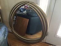 Full view of round framed mirror showing the multi-ridged metallic bronze/gold frame and clear reflective surface.