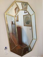 Octagonal mirror with gold frame showing beveled edges, reflecting interior room