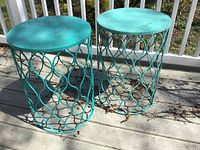 Two matching contemporary metal round outdoor side tables with wave pattern base and turquoise finish, weathered condition