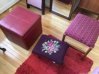 Photo showing red storage ottoman, needlepoint cushioned footstool with floral design, and wooden footstool with pink diamond fabric.