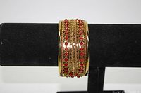 Front view of wide gold tone bracelet showing central gold chain design and red bead rows.