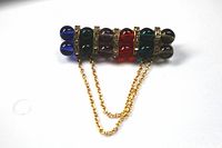 Full view of colorful bead bar brooch with two gold-tone chains visible against a white background.