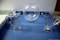Four cut glass pieces displayed on blue surface, includes milk pitcher with lid, rose bud bowl, heart-shaped candy dish and small covered dish.