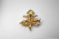 Front view of the Coro gold tone flower brooch showing gold textured petals and red teardrop stone in center.