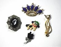 Five brooches displayed together showing overall lot contents.