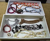 Full view of all jewelry in lot displaying colorful beaded necklaces, chain link necklaces, bracelets, and cameo brooch in a white box