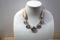 Front view of the rhinestone necklace displayed on a mannequin showing five large round rhinestones on a wide shimmering ribbon.