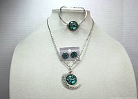 Full set displayed on bust form showing necklace with crescent moon and teal tree pendant, matching bracelet, and earrings on card.