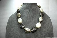 Photo showing the full necklace on a display bust, illustrating the alternating pattern of cream and grey beads with knotted detailing between each bead.