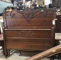 Front view of the wood headboard and footboard showing carved ornate decorative details and overall condition.