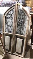 Full view of two-piece rustic decorative doors with metal scroll patterns and wood panels, showing the distressed finish and overall shape.