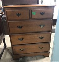 Front view of the four drawer maple wood dresser showing metal pulls and green sticker tag.
