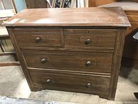 Front view of four drawer wooden dresser showing two small top drawers and two larger bottom drawers with wood pulls