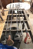 Five golf clubs laid out, showing metal shafts and worn heads of different styles and colors.