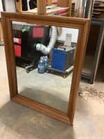 Full view of rectangular wood framed mirror showing the mirror's surface and frame.