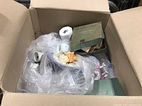 Box with various wrapped ceramic pieces and some small alabaster monuments visible